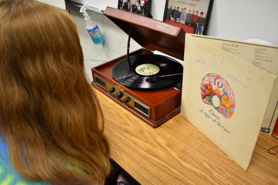 A student listens to Queens A Night at the Opera on a vintage-style record player.