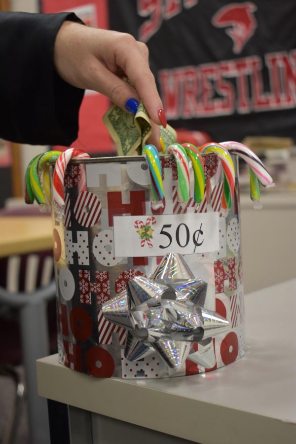 Student buys a candy cane from the bucket in a classroom.