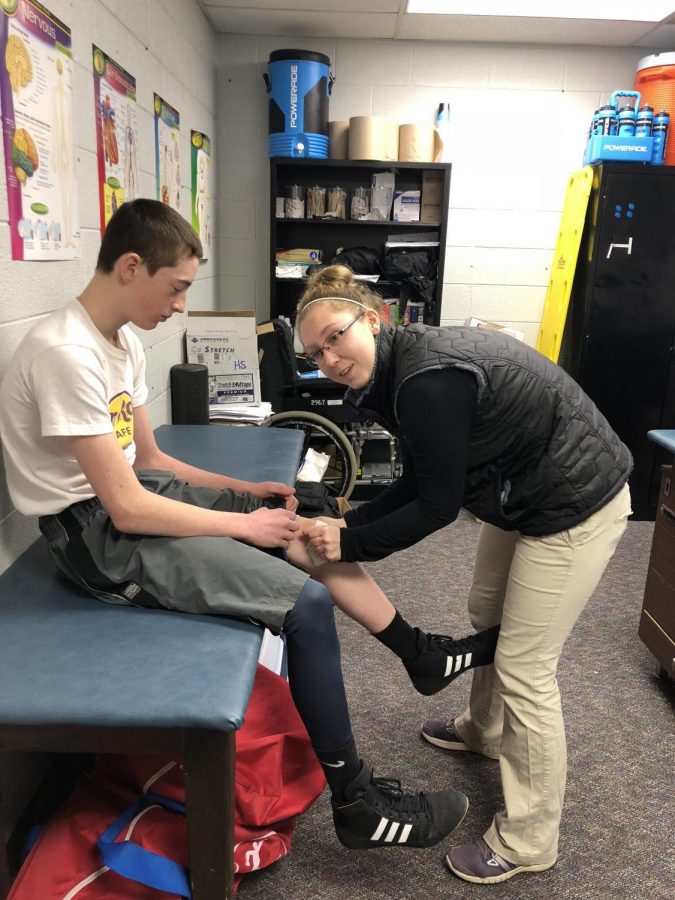 Gabby Bass helps a student with an injury.