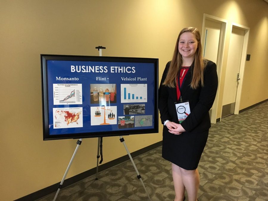 Lauren Sherwood poses next to the visual aid she used for her award-winning speech.