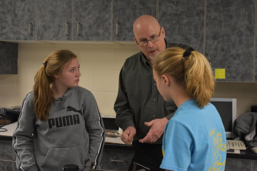 Mr. Stedman helps two students.