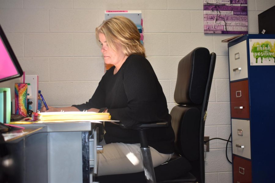 Mrs. Sura sits at her desk while working hard. 