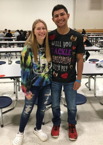 Martine Wiggins stands with his homecoming date, Kiersten Wenzlick, while wearing his hoco proposal shirt that reads Will you tackle homecoming with me?