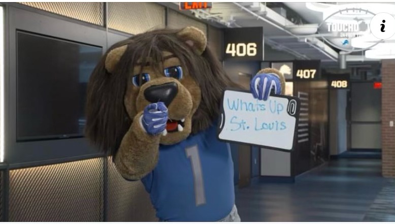 Detroit Lions mascot poses with a sign that says a little message to St. Louis.
