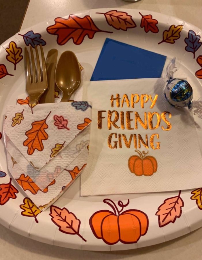 A student sets up her table with festive plates and napkins for her Friendsgiving dinner.  