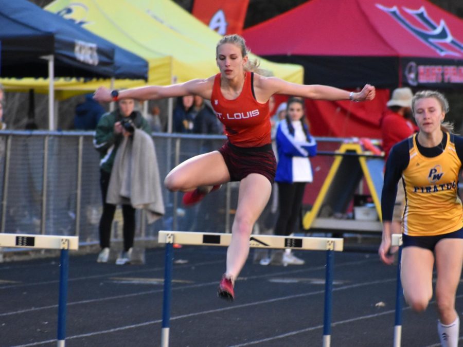 Munderloh jumps over a hurdle at a track meet.