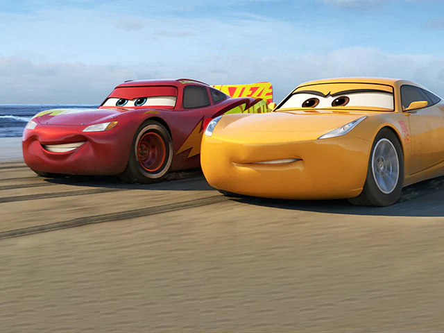Lightning McQueen and Cruz Ramirez practice racing along the shore.