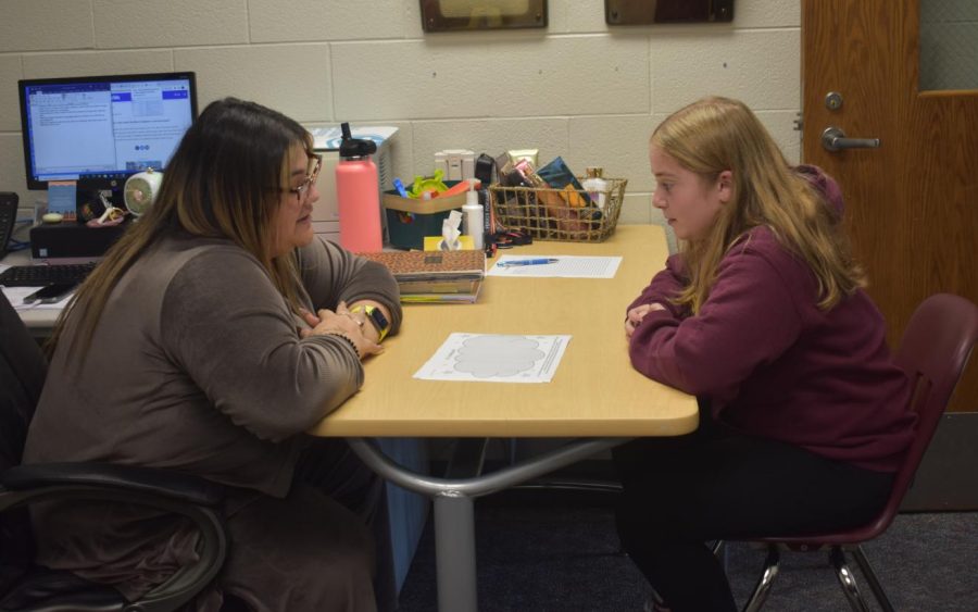 Miss Navarro sits with a student in her office.
