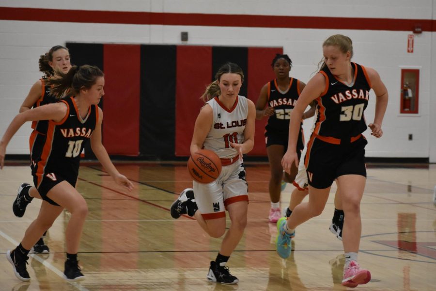 Natalee Hoty takes the ball down the court as Vassar players try to steal the ball. 