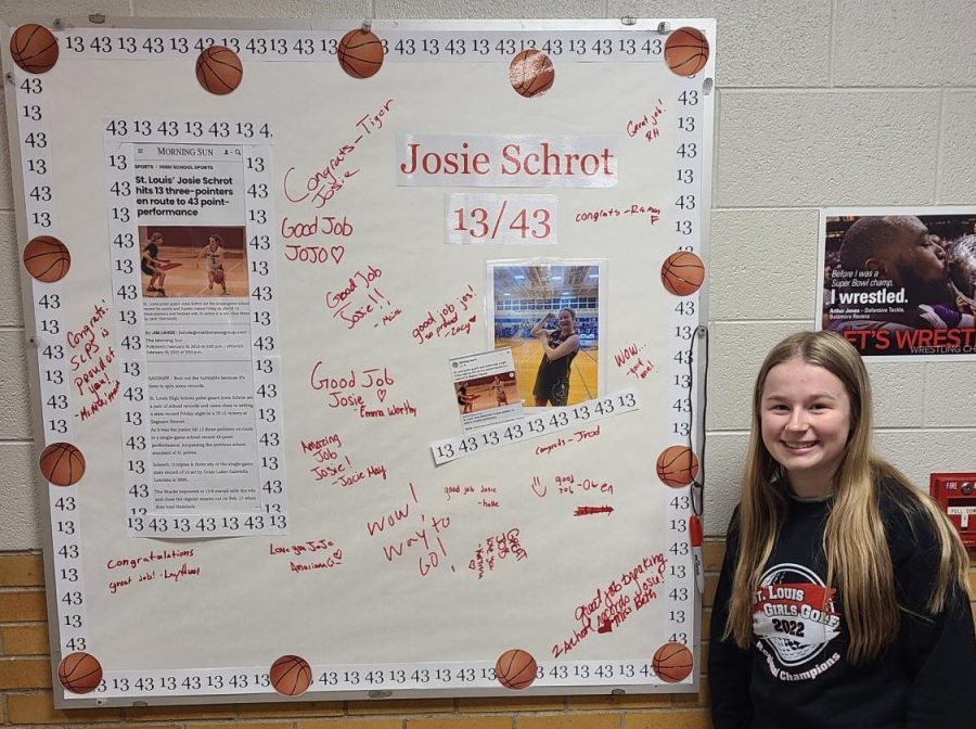 Josie Schrot poses next to the bulletin board dedicated  to her accomplishments.
