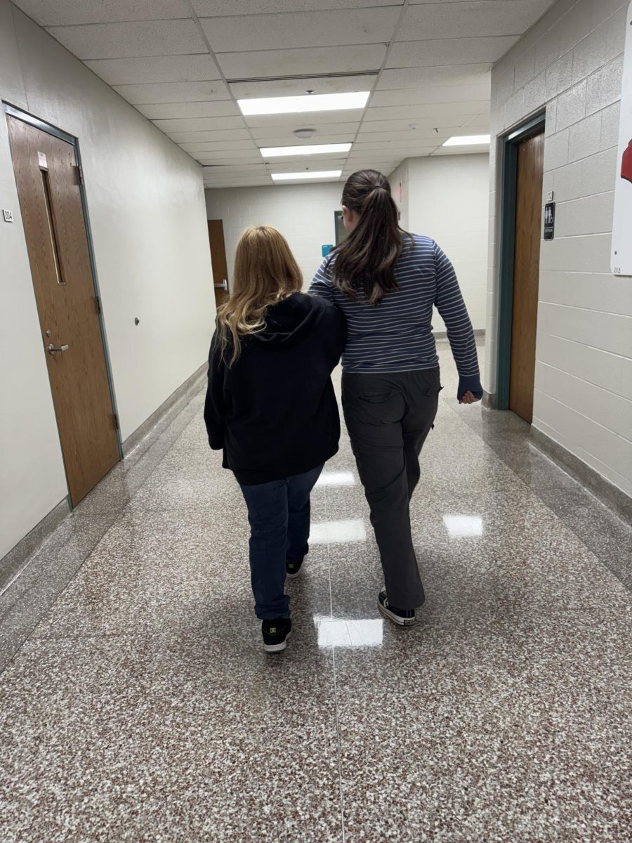 Two students take a stroll in the hallway, holding hands.