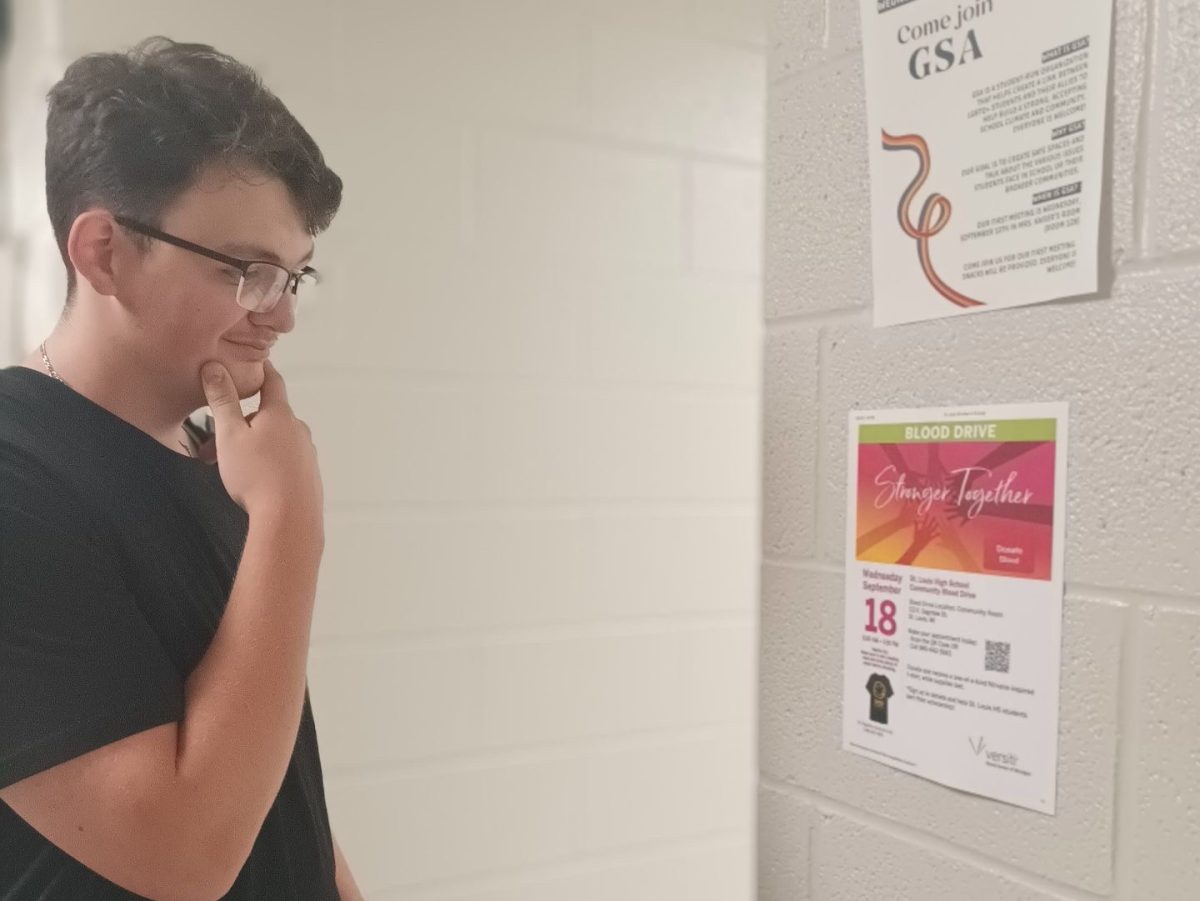 Senior Damian Rosenberger reads the information on the blood drive poster.