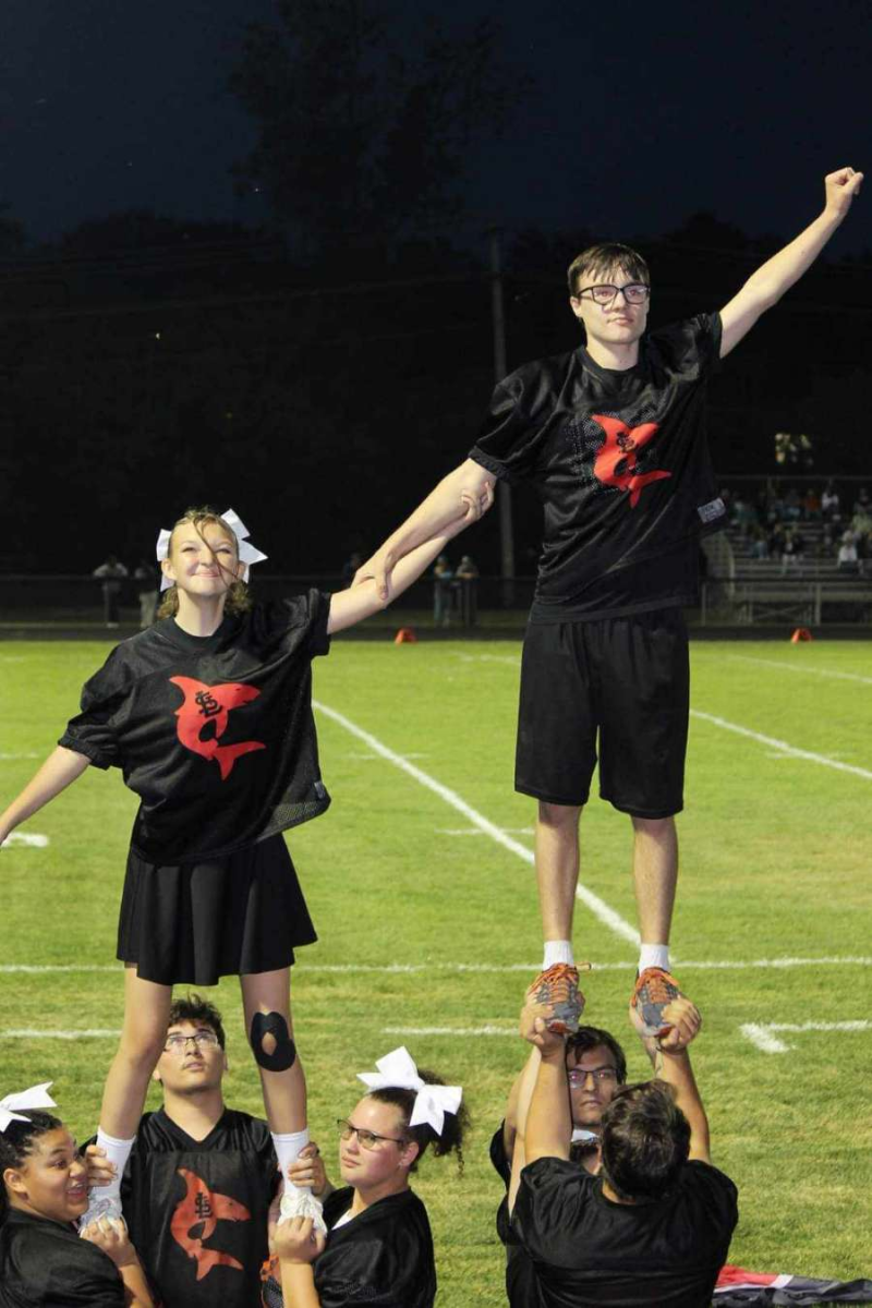 The cheer team perfectly executes a well-practiced stunt in front of the crowd!