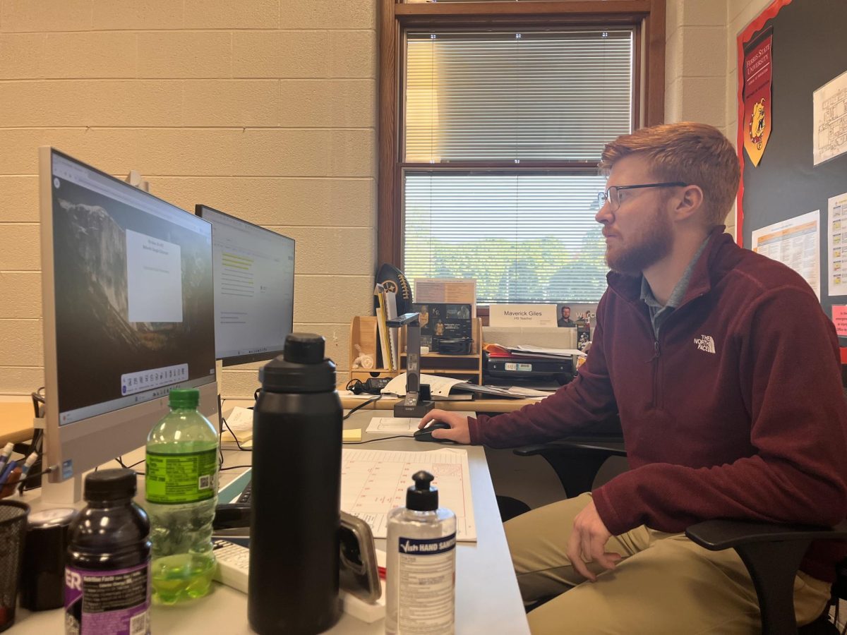 Mr. Giles works hard at his desk, grading.