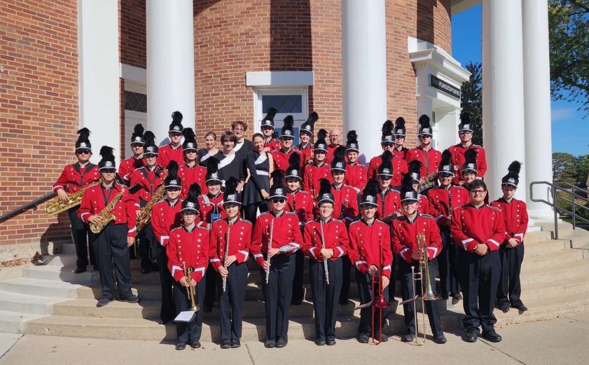 The band altogether, in their uniforms, smiling for a picture.