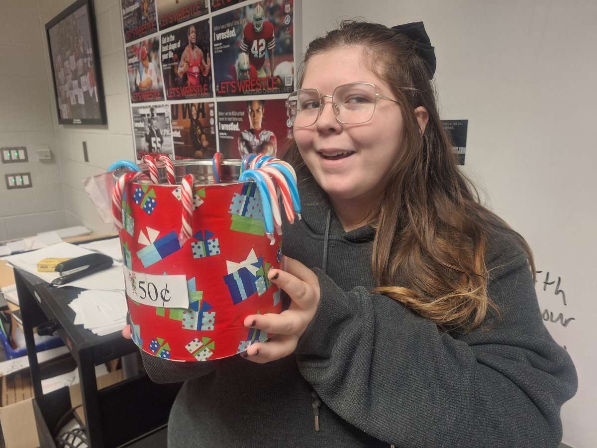 Junior Leia Firman showcases one of the cans of candy canes available for purchase.