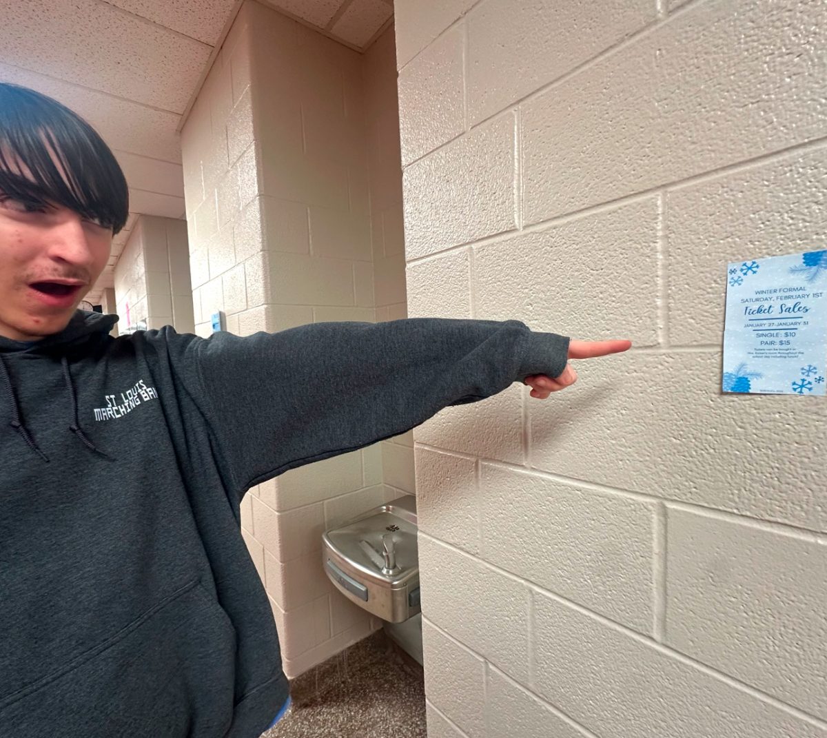 Junior Noah Bobzien points out the flyer for the upcoming winter formal.