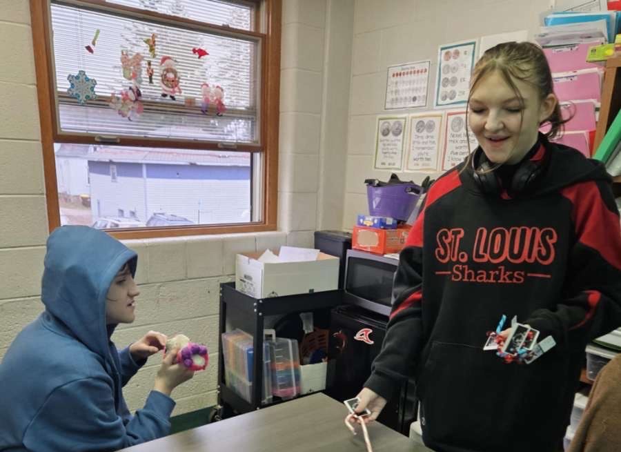 Senior Kaydence Heiden gives out candy to a student as a part of the new club.