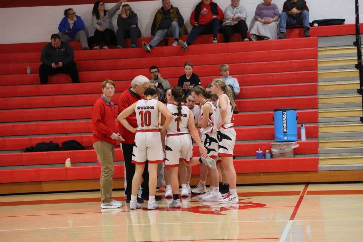 The girls basketball team converses about their approach to the next quarter.