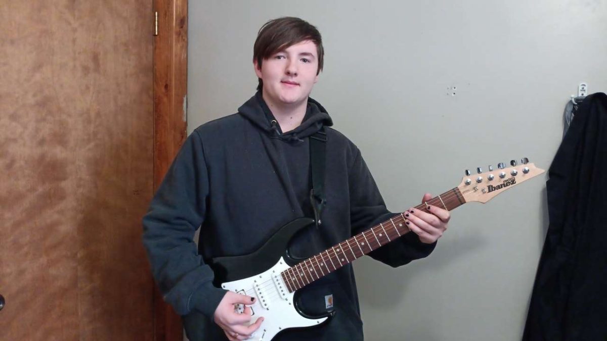 Senior Elliot Carter stands with his guitar, ready to play.