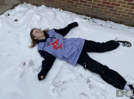 Senior Kaydence Heiden lays in the recent snowfall.