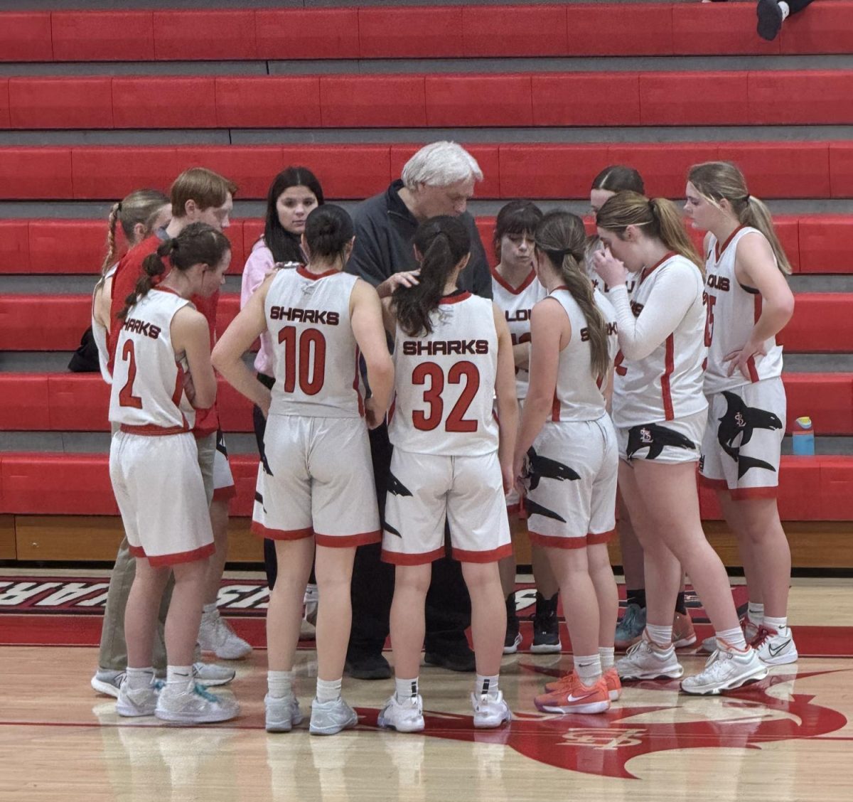 The girls basketball team talks in a huddle during a time out.