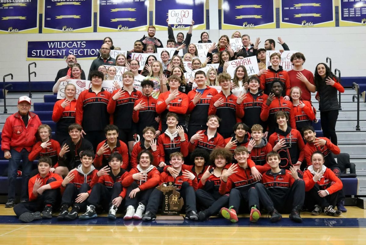 The wrestling team takes a proud photo with the greatly-spirited student section after a successful day of wrestling.