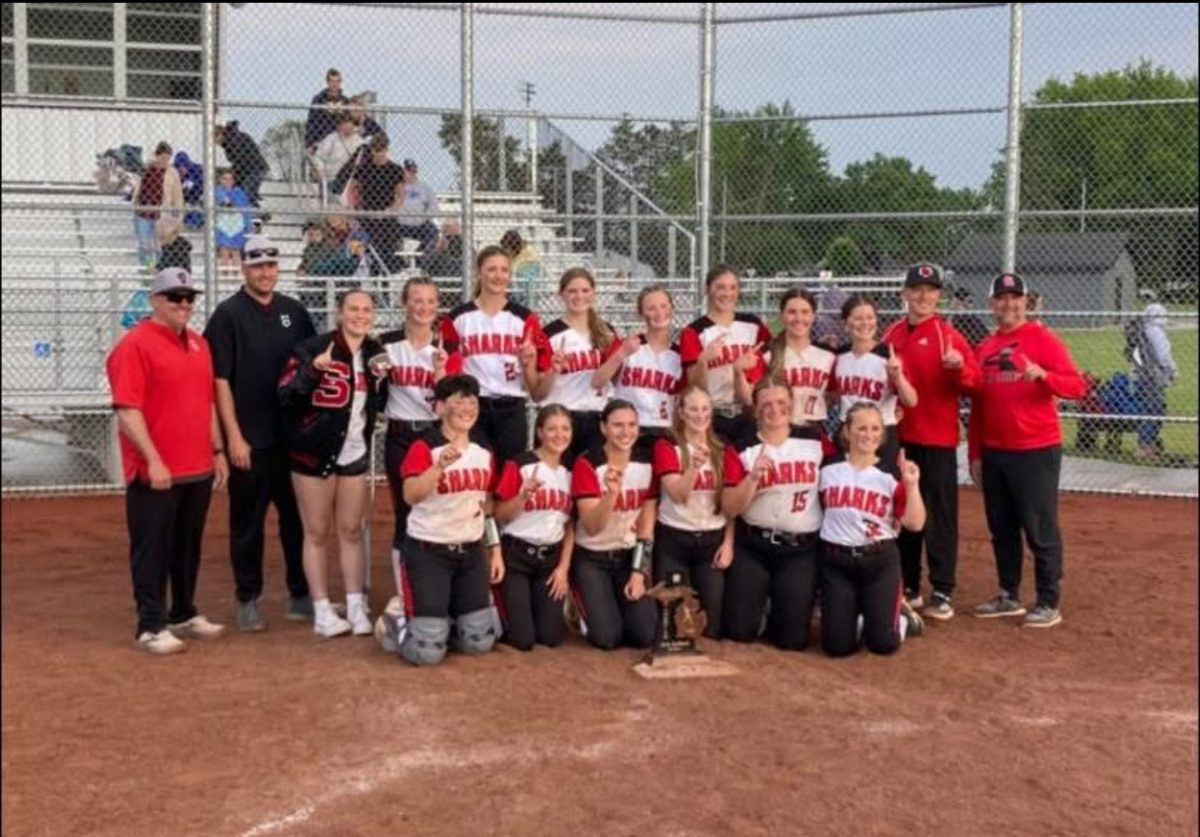 The softball grouped together in picture, celebrating their victory.